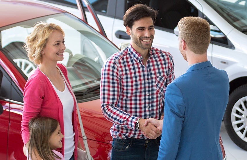 Customers shaking car salesman hand